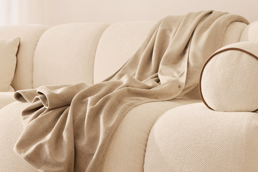 Unfolded EMF blanket draped over a beige sofa